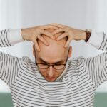 person rubbing tired eyes at computer